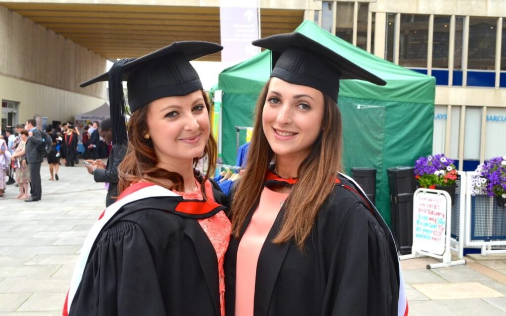 Two smiling graduates at convocation, representing post-graduation work permits in Canada